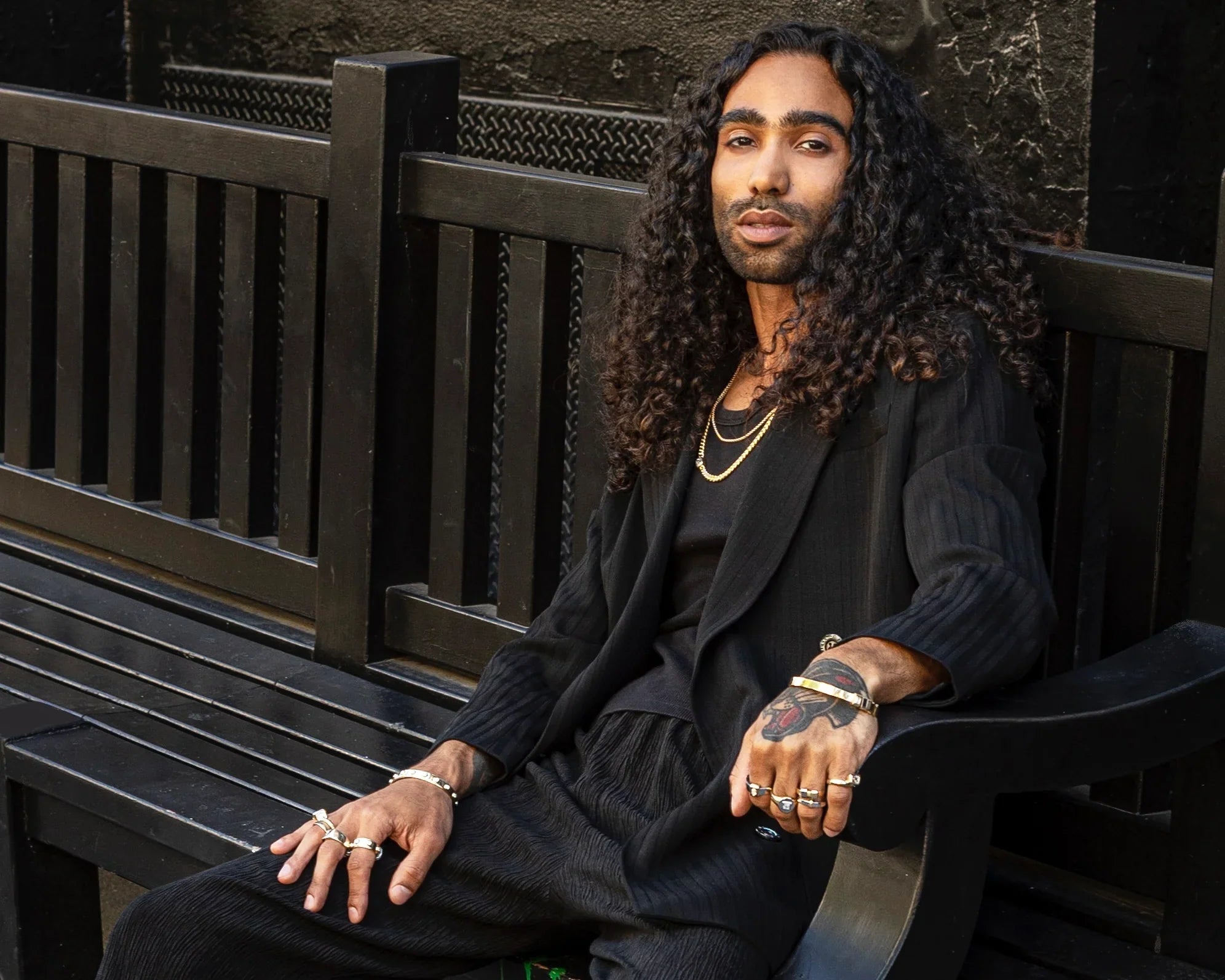 model in black suit with gold chains and rings