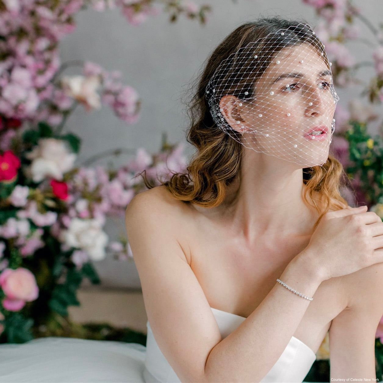 bride in wedding dress with veil and flowers in background
