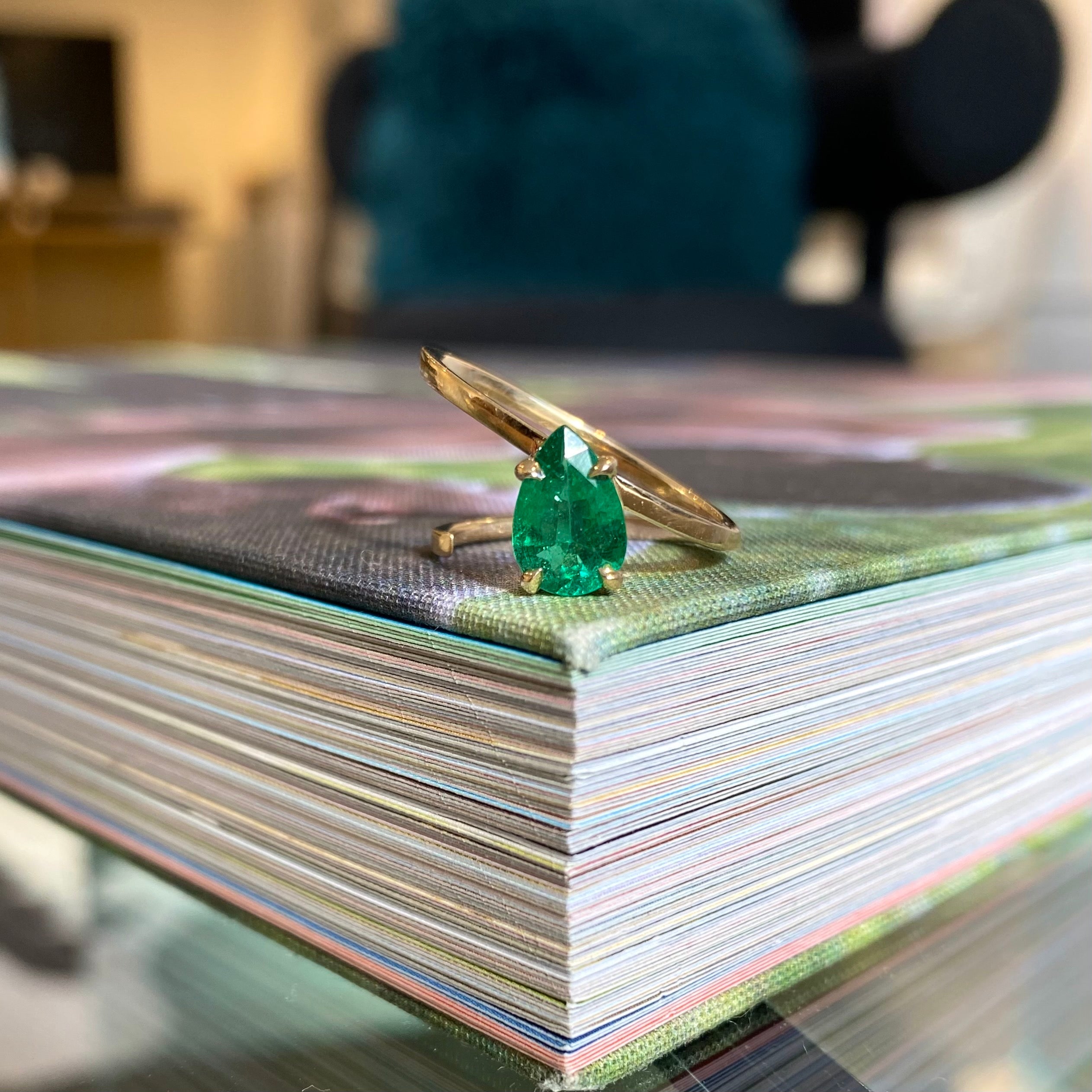 slant ring with emerald pear on book