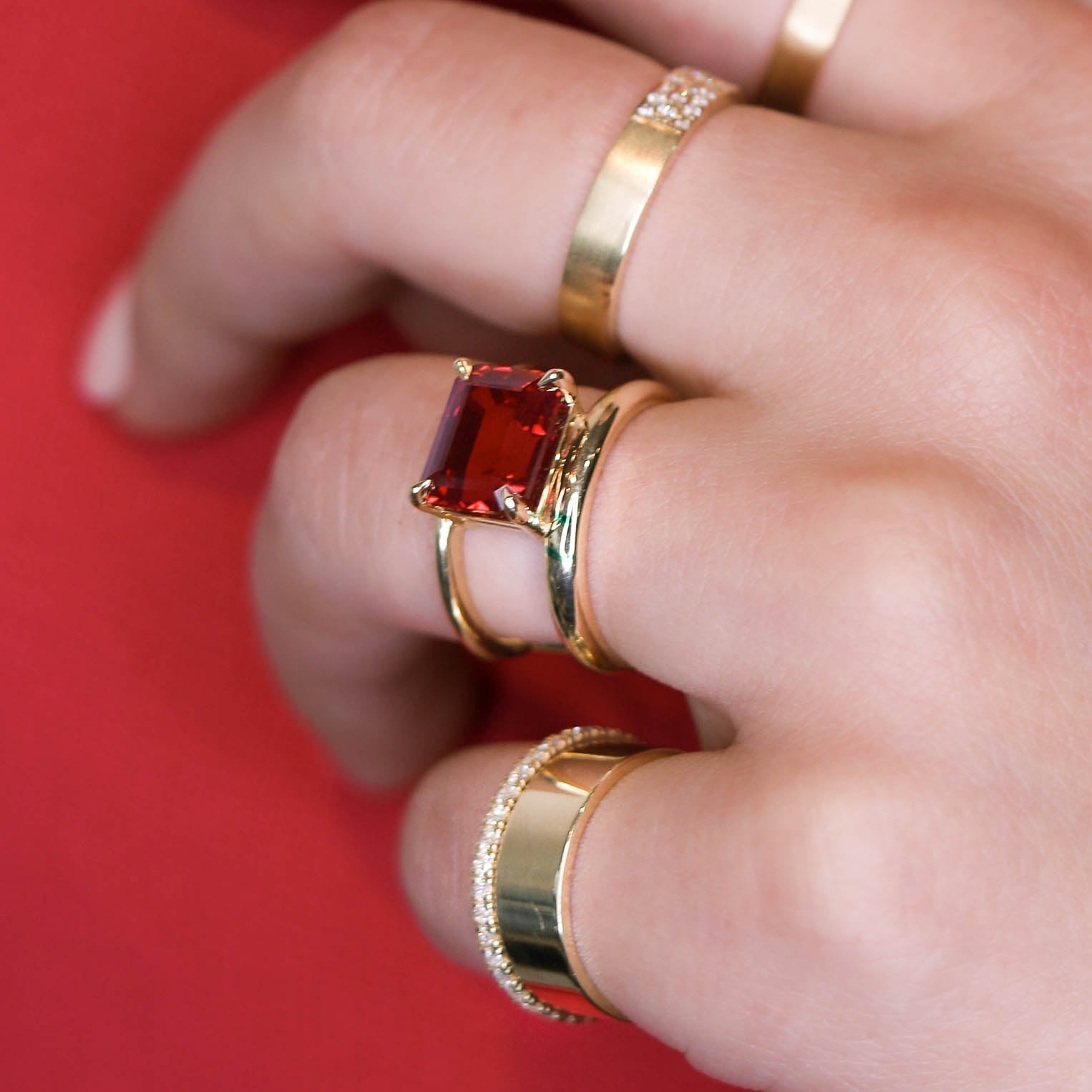 gold bands and ruby stone on hand with red background