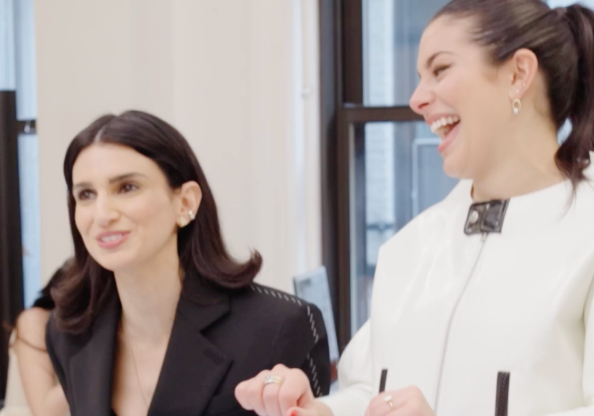 Two women sitting together, smiling and engaged in conversation.