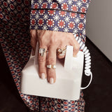 Hand wearing 5 rings by Shahla Karimi made in yellow gold with diamonds holding telephone