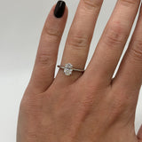 Diamond ring on a finger against a neutral background