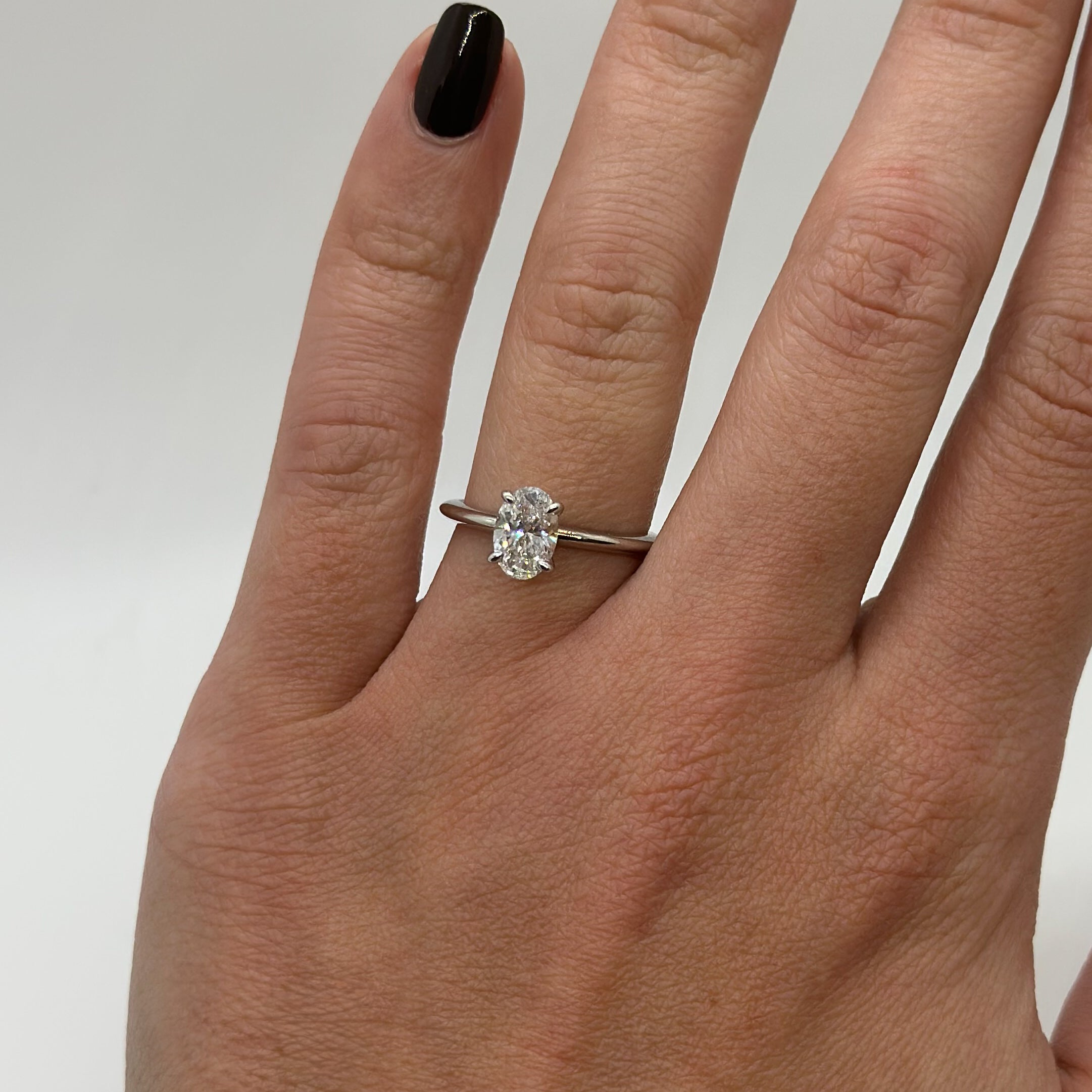 Diamond ring on a finger against a neutral background