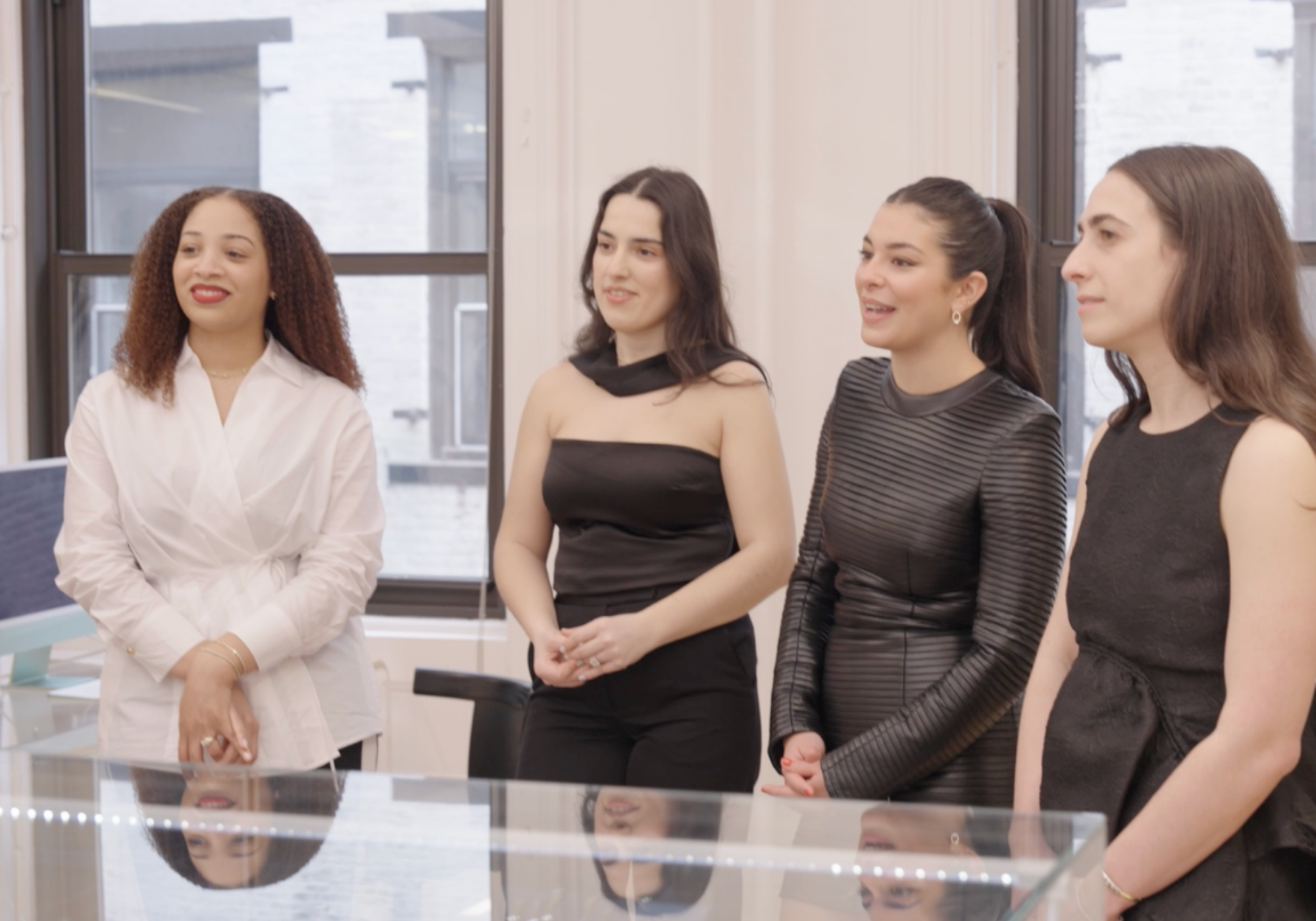 Four women standing in a row in an office setting