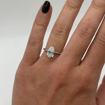 Hand wearing a diamond ring on a neutral background