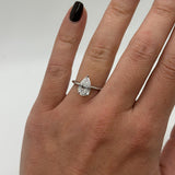 Hand wearing a diamond ring on a neutral background
