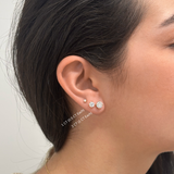 Close-up of person wearing white gold stud earrings with round-cut diamonds, text that reads 1ct and 2ct
