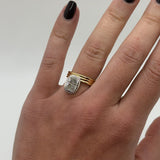 Hand wearing a gold ring with a diamond on a neutral background