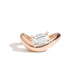 An emerald diamond ring with a sculptural rose gold band, presented against a white background.