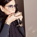 Person on the phone sipping from champagne glass wearing Shahla Karimi jewelry