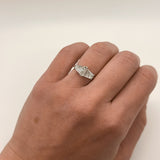 hand with a diamond ring with two trapezoid diamonds on a white background