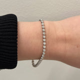 white gold bezel set tennis bracelet on wrist with neutral background