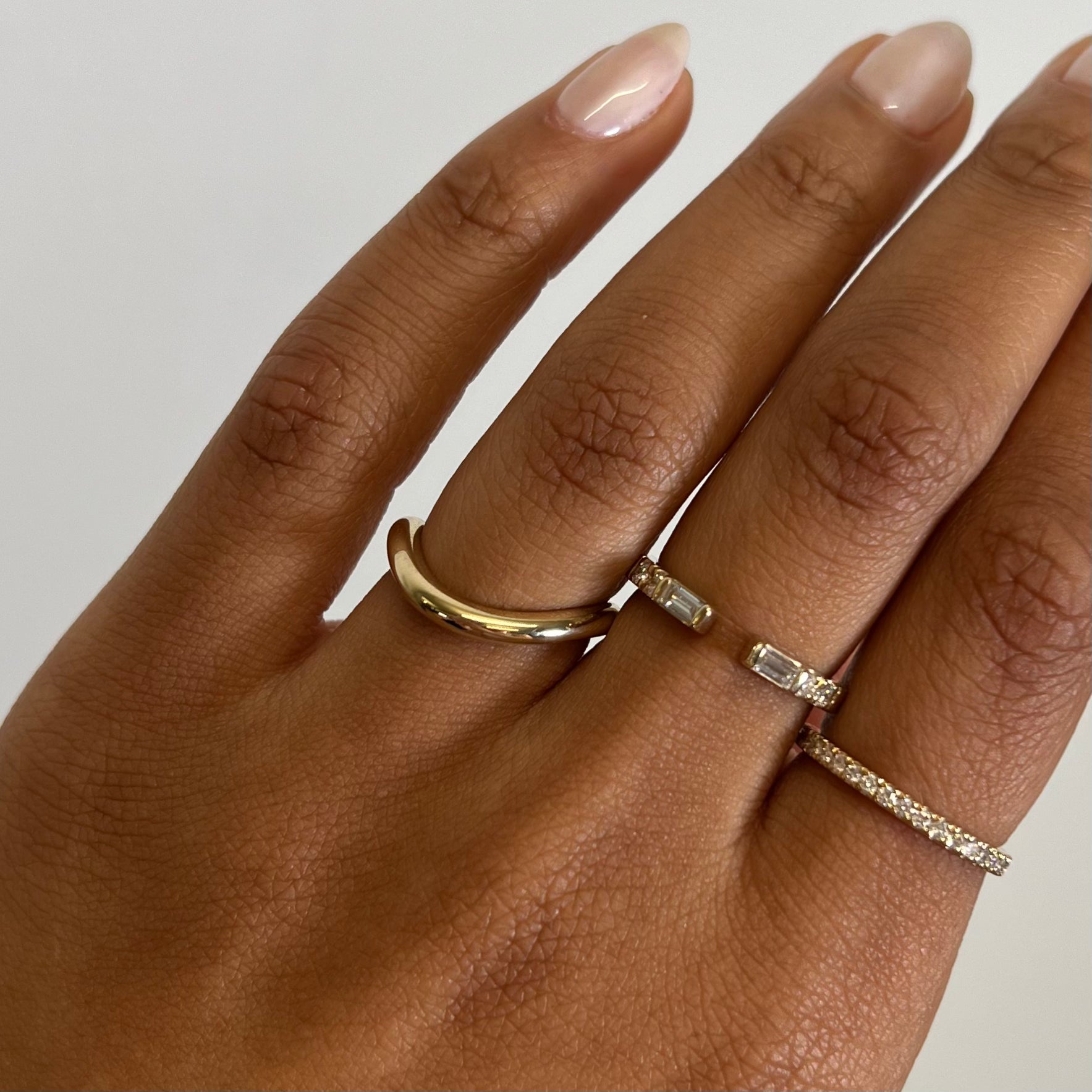 Offset Cloud Wedding Band by Shahla Karimi on hand on white background with two other yellow gold and diamond bands
