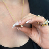 Person wearing and holding elongated pendant of the letter K