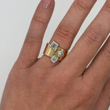 Gold ring with square gemstones on a hand against a white background