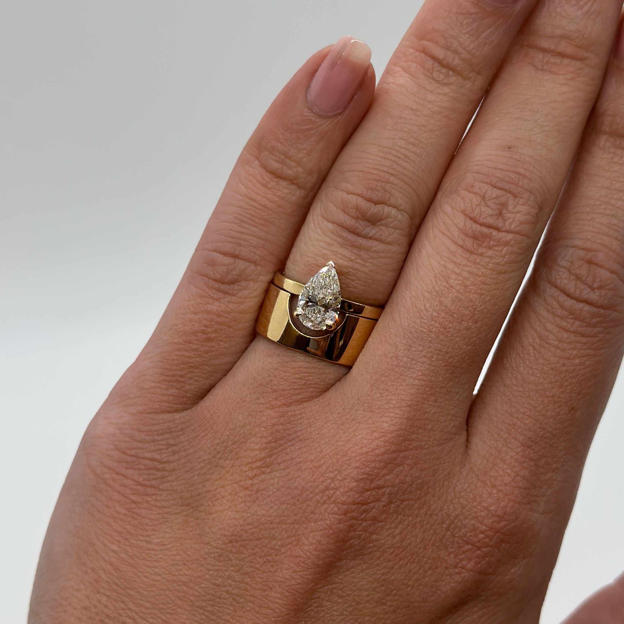 Gold ring with a diamond on a hand against a neutral background