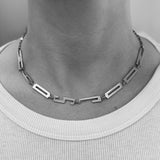 Geometric necklace worn by a person on a plain background