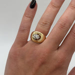 Gold ring with a diamond on a hand against a neutral background