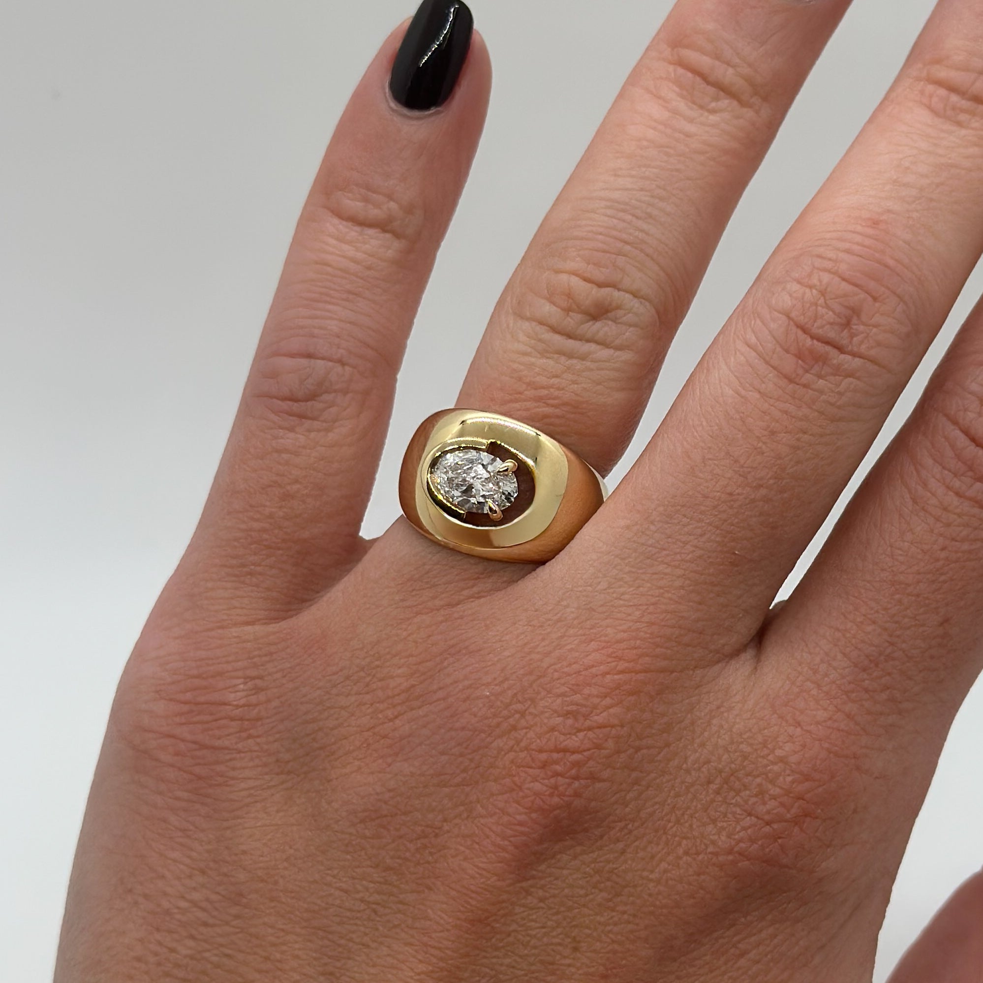 Gold ring with a diamond on a hand against a neutral background