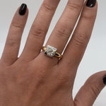 Gold ring with a diamond on a hand against a neutral background