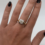 Gold ring with a diamond on a hand against a neutral background
