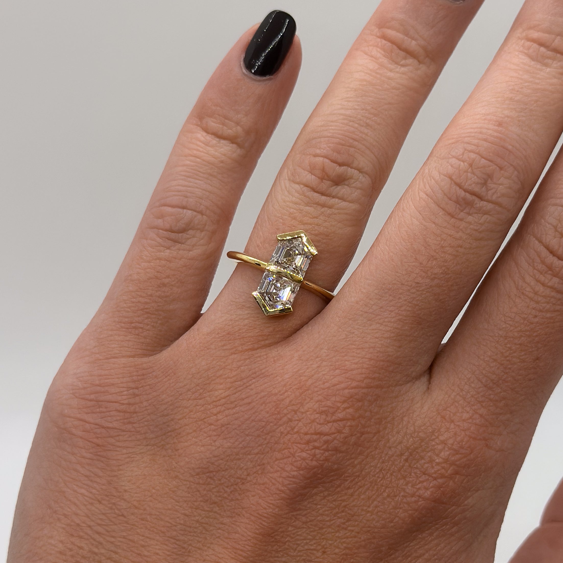 Gold ring with a diamond on a hand against a neutral background