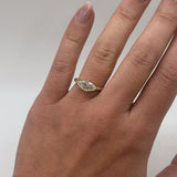 marquise diamond in yellow gold band on hand with neutral background