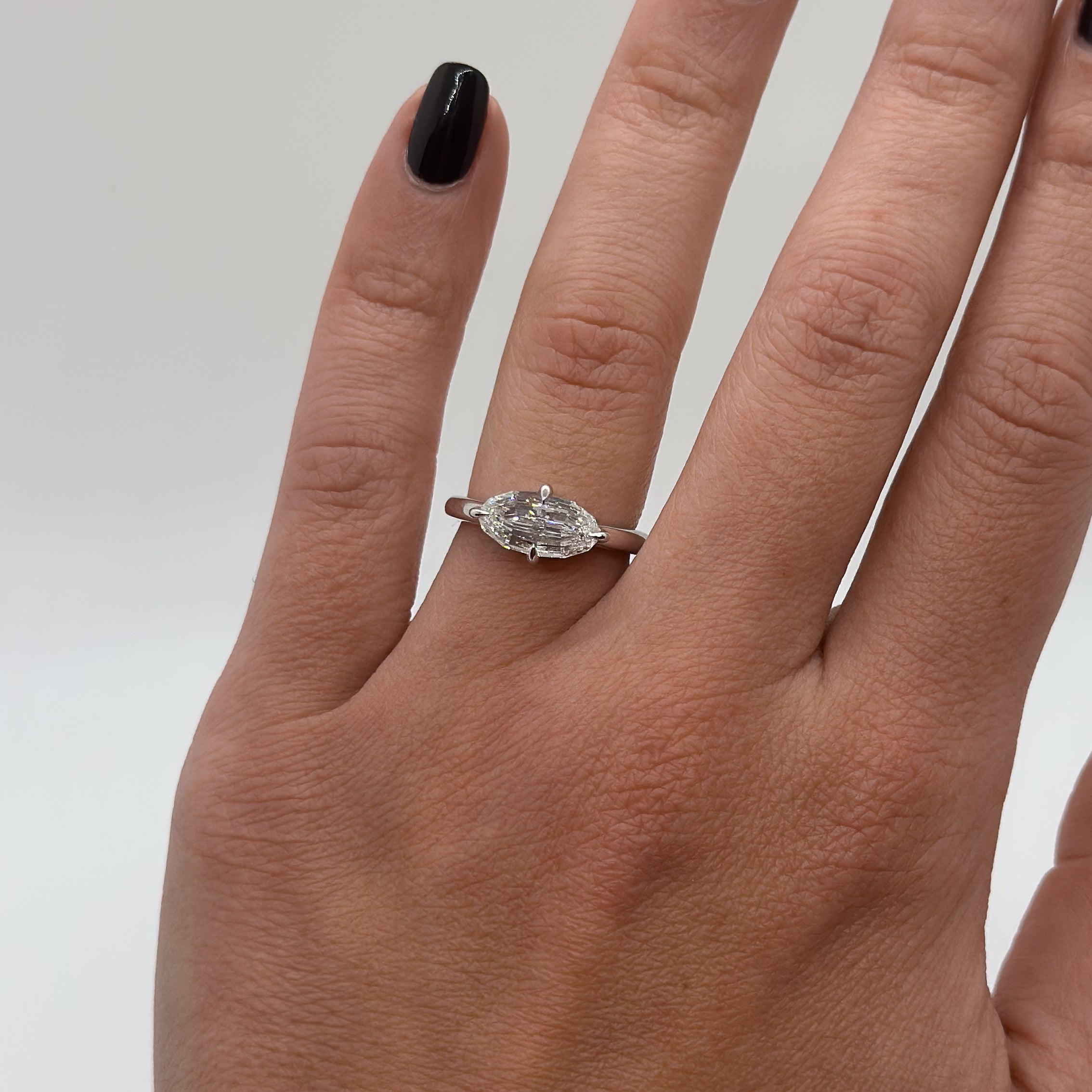 Hand wearing a diamond ring on a plain background