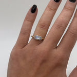 Gold ring with a diamond on a hand against a neutral background