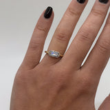 Gold ring with a diamond on a hand against a neutral background