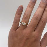 Gold ring with a diamond on a hand against a plain background