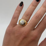 Gold ring with a diamond on a hand against a neutral background