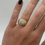 Gold ring with a diamond on a hand against a neutral background