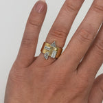 Gold ring with diamond accents on a finger against a neutral background