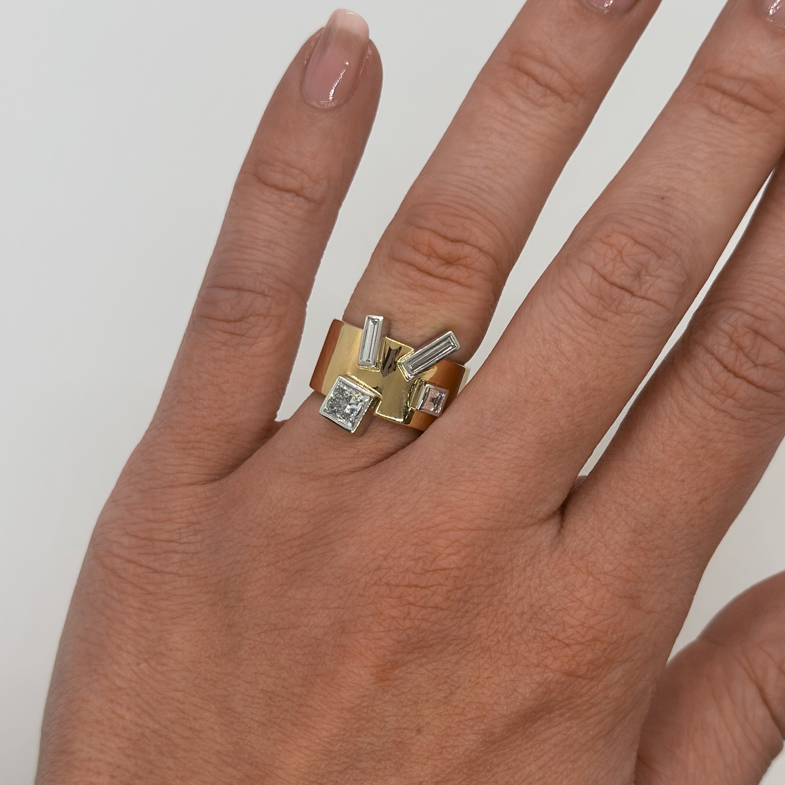 Hand wearing a gold and silver ring on a plain background