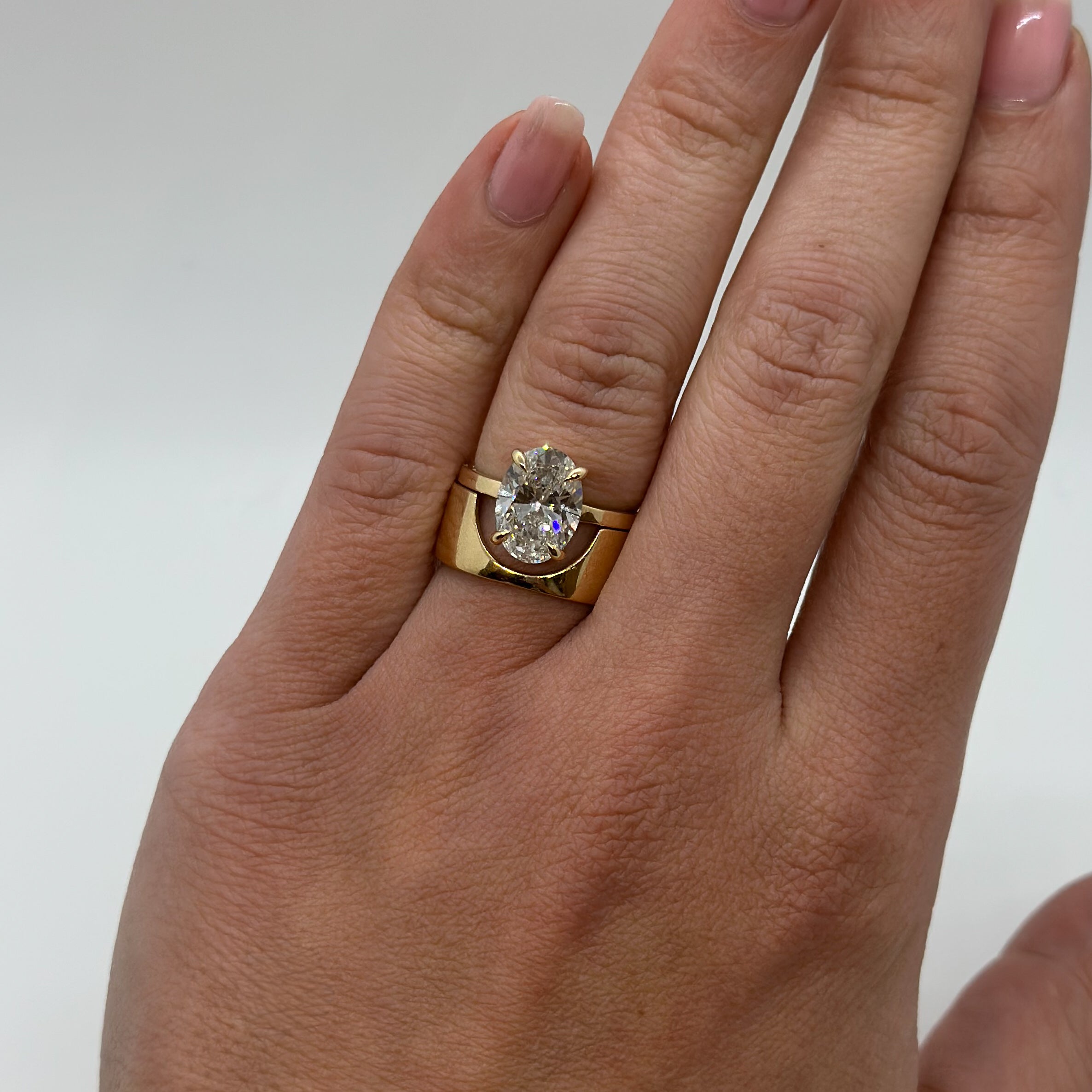 Gold ring with a diamond on a hand against a white background