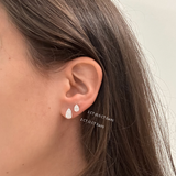Close up of ear with two pear-cut diamond studs, 1ct and 2ct