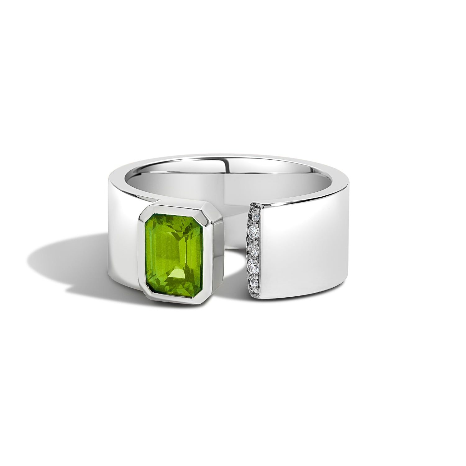 A silver-toned wrap ring featuring a large rectangular green peridot gemstone on one side and a row of small clear stones on the other, set against a clean white background.