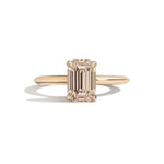 gold ring with a champagne emerald-cut diamond on a white background