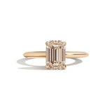 gold ring with a champagne emerald-cut diamond on a white background