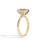 gold ring with a champagne emerald-cut diamond on a white background
