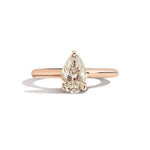 Gold ring with a pear-shaped diamond on a white background