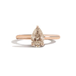 Rose gold ring with a pear-shaped diamond on a white background