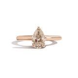 Rose gold ring with a pear-shaped diamond on a white background