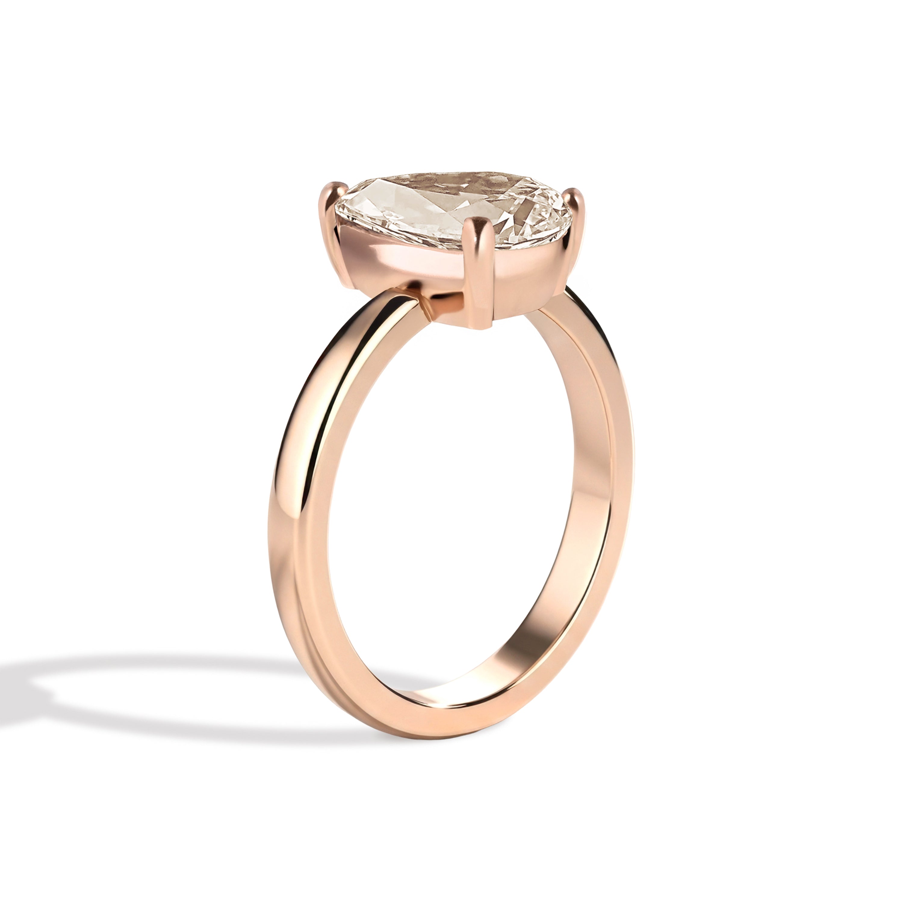 Gold ring with a pear-shaped diamond on a white background
