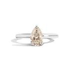Gold ring with a pear-shaped diamond on a white background