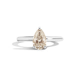 Gold ring with a pear-shaped diamond on a white background