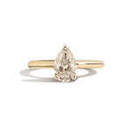Gold ring with a pear-shaped diamond on a white background