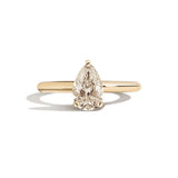 Gold ring with a pear-shaped diamond on a white background